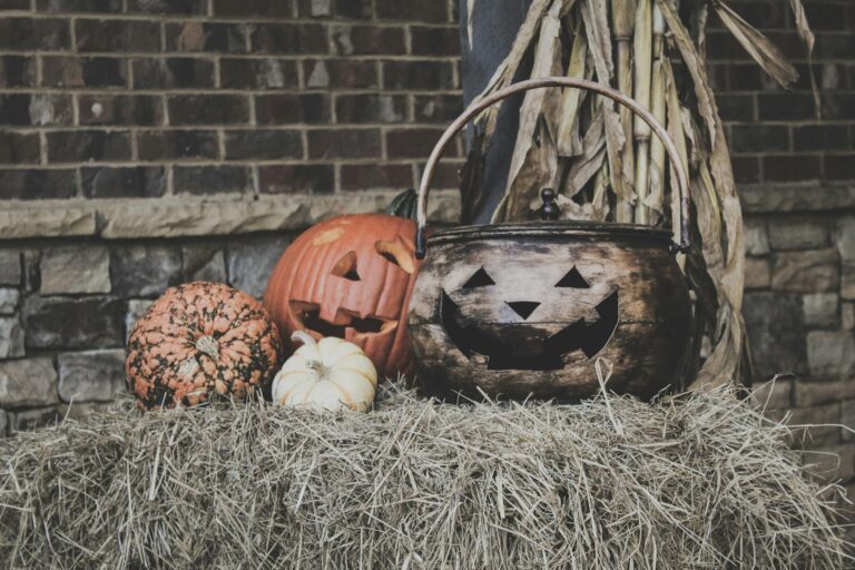 Festive Halloween scene with jack-o'-lanterns and cauldron on hay bale.