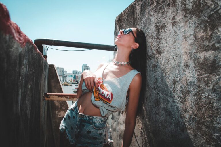 Stylish woman in sunglasses poses on a sunny urban rooftop.