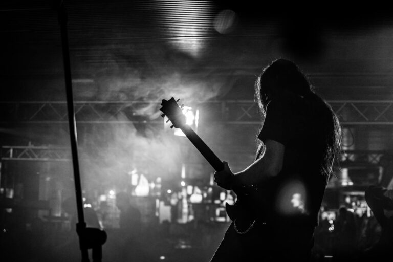 Silhouette of a guitarist performing live at a concert in Milan, Italy.