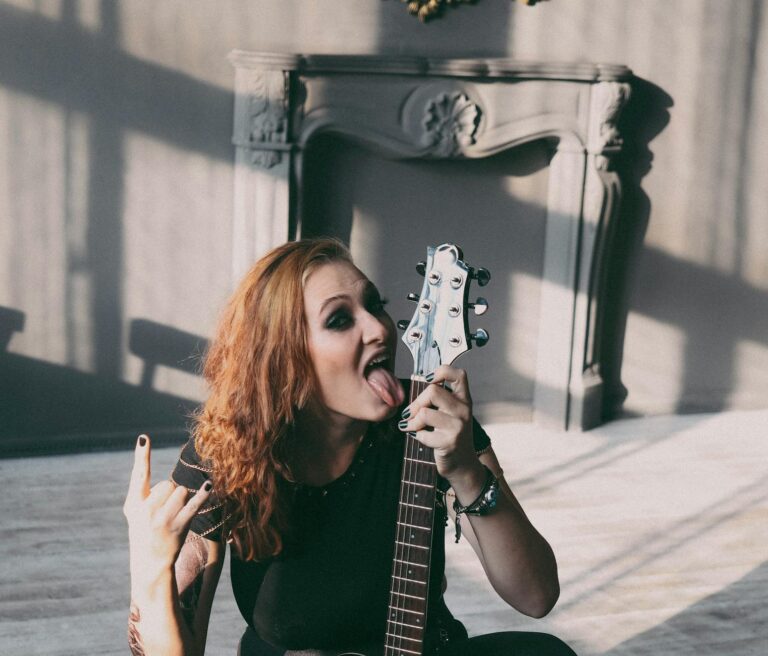 Playful female guitarist in indoor setting expressing rock spirit.