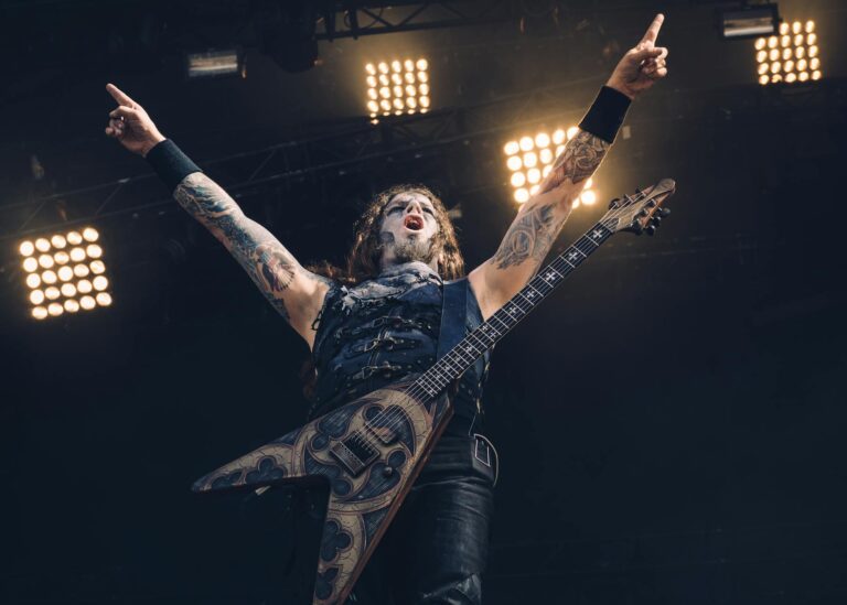 Energetic rock musician with tattoos playing electric guitar during live performance.