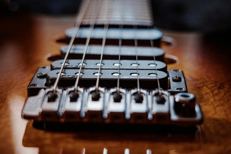 Detailed close-up of electric guitar strings and bridge with a focus on texture and lighting.