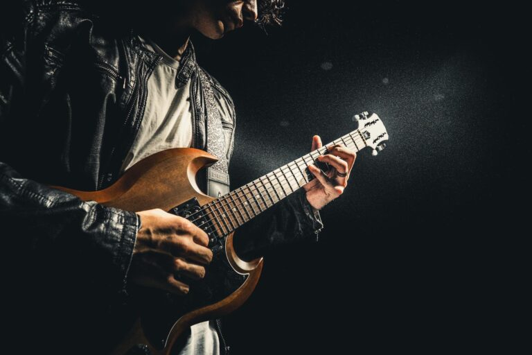 A rock guitarist in a leather jacket passionately playing an electric guitar under dramatic lighting.