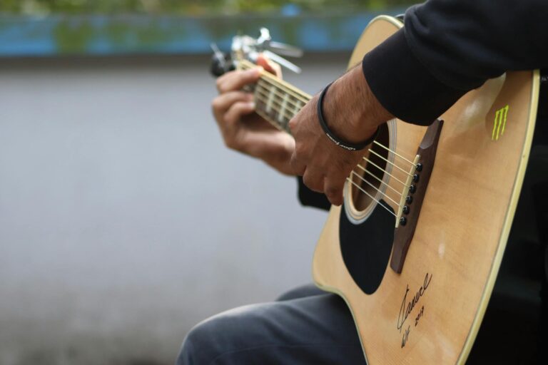 Close-up of hands strumming an acoustic guitar outdoors, capturing the essence of music and creativity.