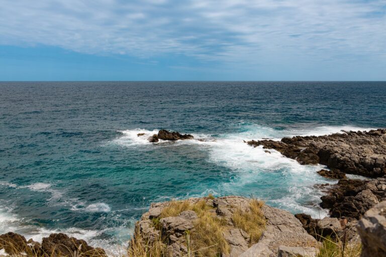 Explore the vibrant blue sea and rocky shore of Palermo, Sicily's stunning coastal scene.