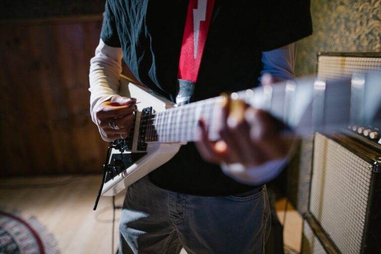 Close-up of a musician playing an electric guitar indoors, focus on hands and instrument.