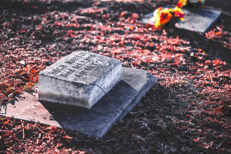 A peaceful autumn cemetery scene with a weathered tombstone and vibrant leaves.