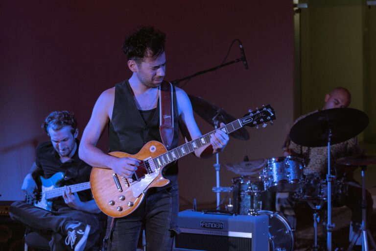 Musicians playing guitar and drums during a live rock concert on stage.