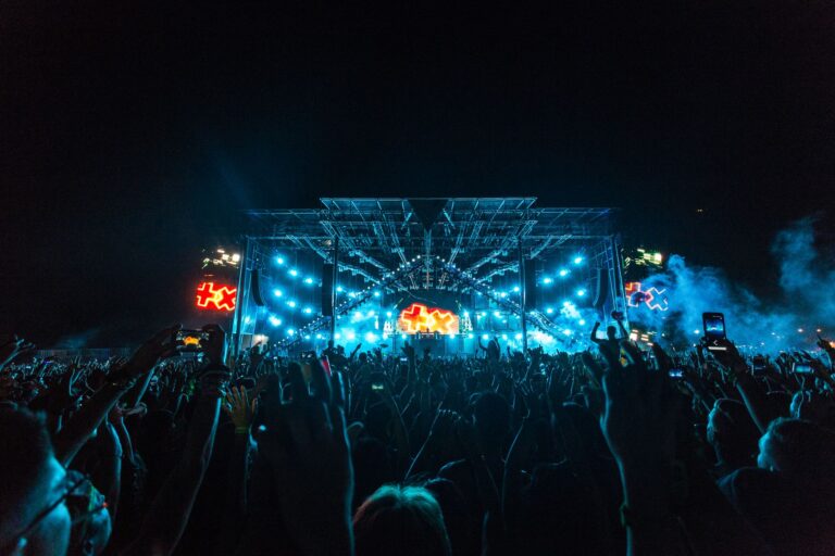 Vibrant crowd enjoying an epic concert under bright stage lights with smoke effects.