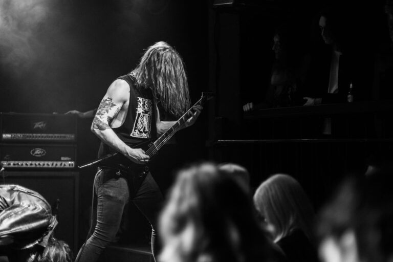 Energetic black and white photo of a guitarist rocking on stage during a live concert.