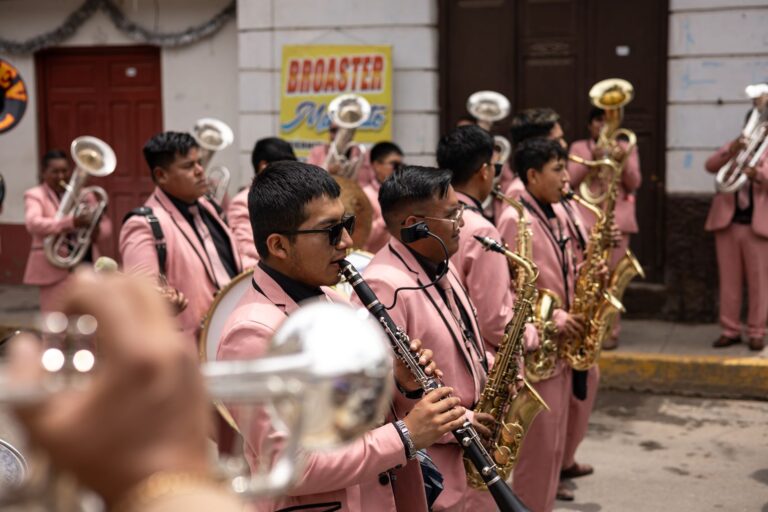 Brass band in pink suits performing on a lively city street parade.