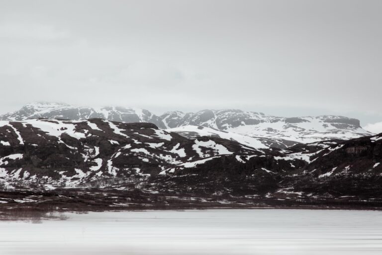 Serene view of snow-capped mountains in Norway during winter, showcasing rugged landscapes.