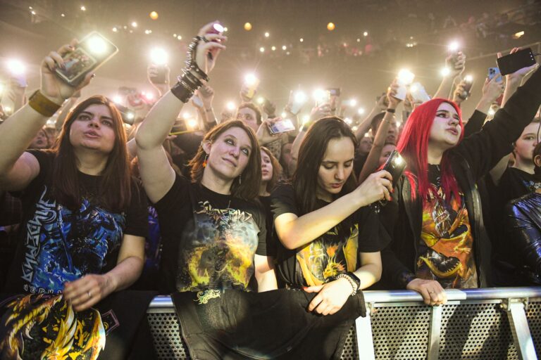 Fans enjoying a live rock concert, capturing moments with cell phones.