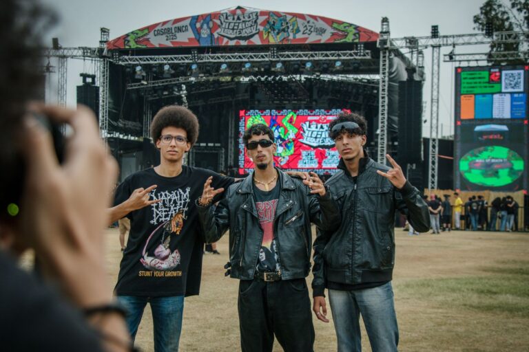 Three young men pose confidently at an outdoor music festival in Casablanca, Morocco.