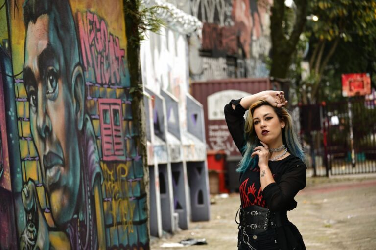 A stylish woman poses confidently in front of vibrant urban graffiti art in an outdoor setting.