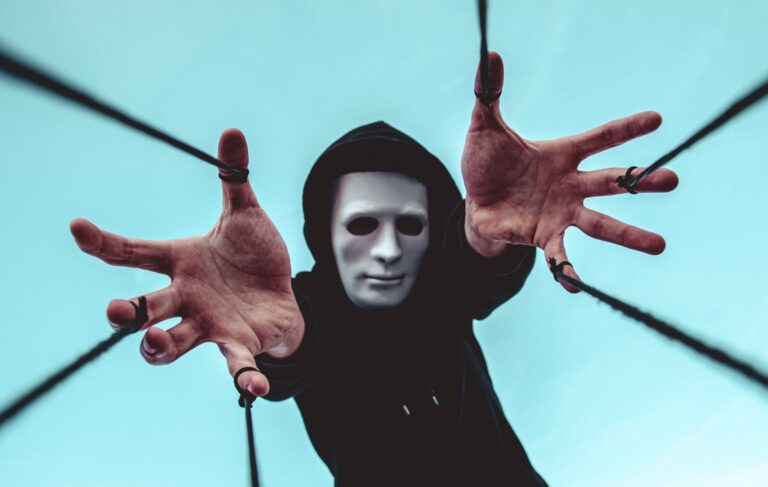 A masked figure extends hands towards the camera, creating a sense of mystery and intrigue.