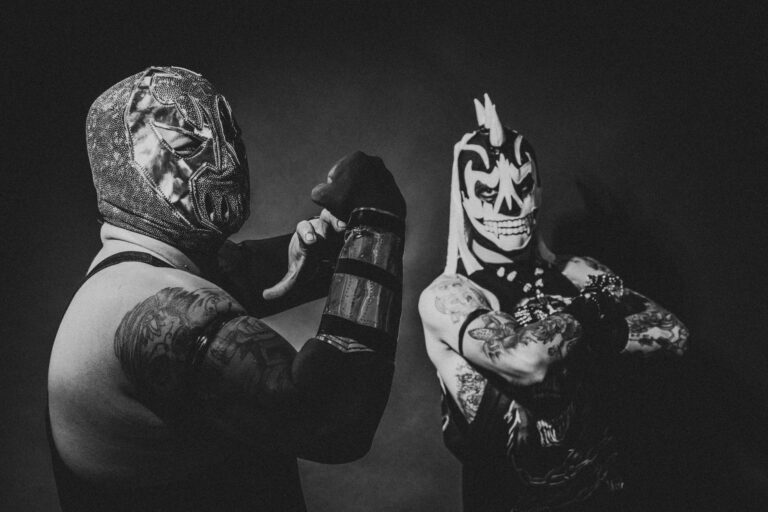 Two masked luchadores showcasing dynamic poses in dramatic black and white.