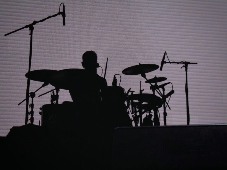 Dramatic silhouette of a drummer performing on stage, highlighting music and performance themes.