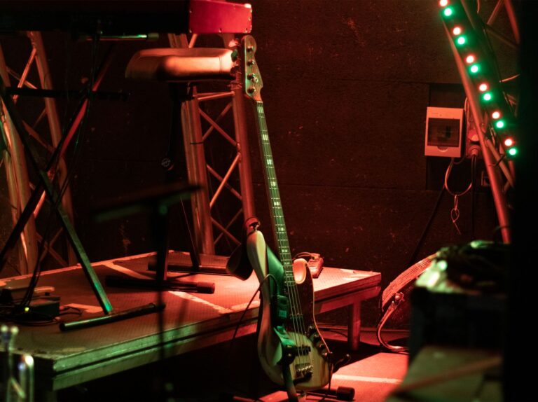 An atmospheric stage with a bass guitar and vibrant strip lights, ready for a live performance.